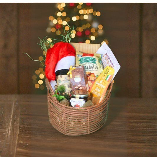 Cesta redonda com panetone, bruschetta, conservas e enfeites de natal