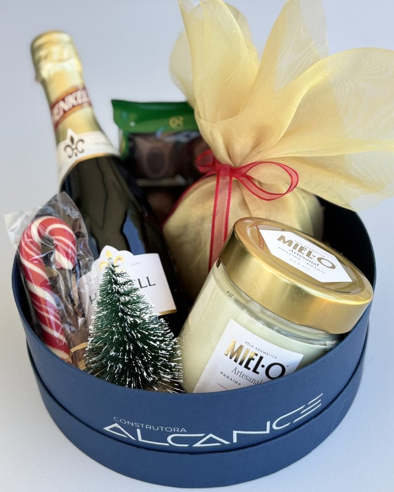 Caixa azul da Construtora Alcance com espumante, vela aromática, chocolates, panetone e enfeite de Natal