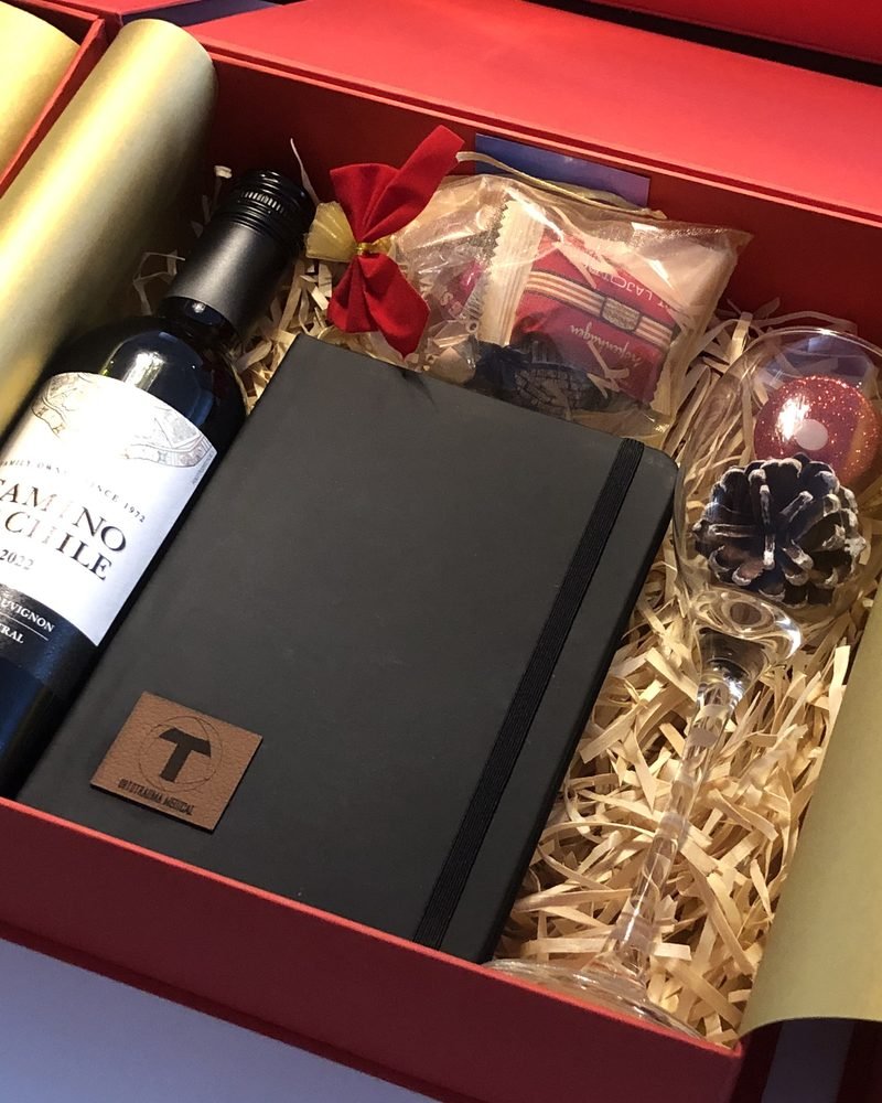 Caixa vermelha com vinho, caderno personalizado, taça e enfeites