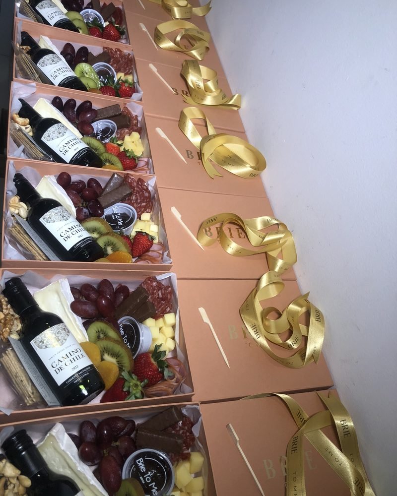 Boxes Brie To Me com vinho, frios e frutas, fechados com laço dourado