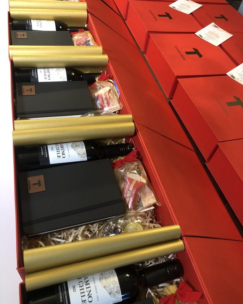Caixas vermelhas com vinho, caderno e taça montadas para um pedido corporativo
